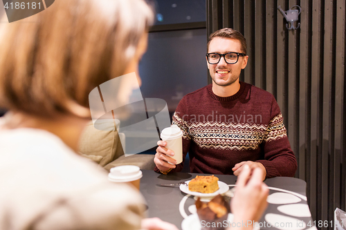 Image of happy couple with coffee eating cake at cafe