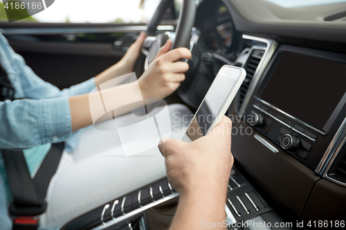 Image of happy man and woman with smartphone driving in car