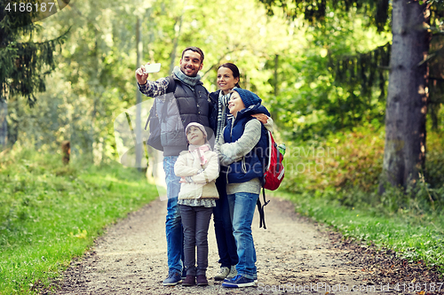 Image of family taking selfie with smartphone in woods