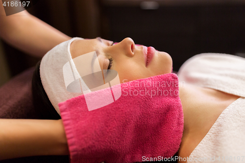 Image of woman having face massage with terry gloves at spa