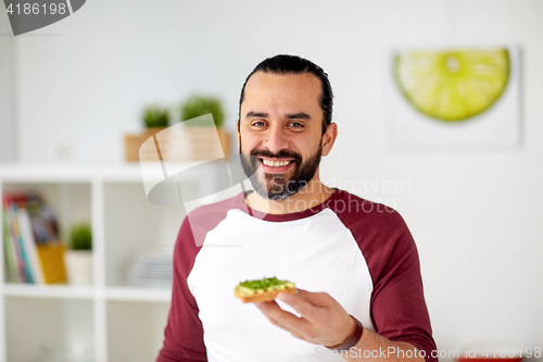 Image of man eating avocado sandwiches at home kitchen