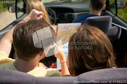 Image of happy friends with map driving in convertible car