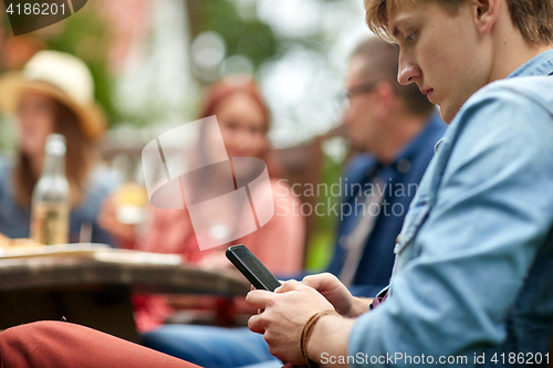 Image of man with smartphone and friends at summer party