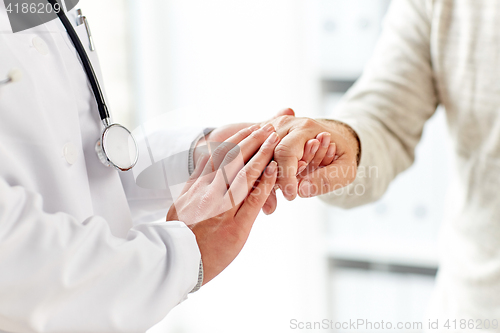 Image of close up of doctor holding old man hand