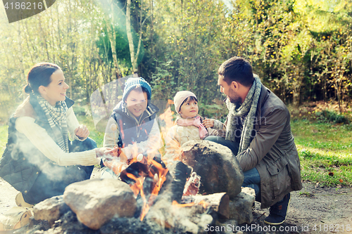 Image of happy family roasting marshmallow over campfire