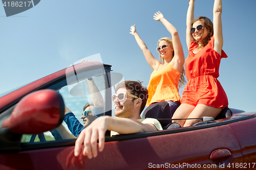 Image of happy friends driving in cabriolet car at country