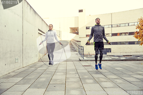 Image of man and woman exercising with jump-rope outdoors