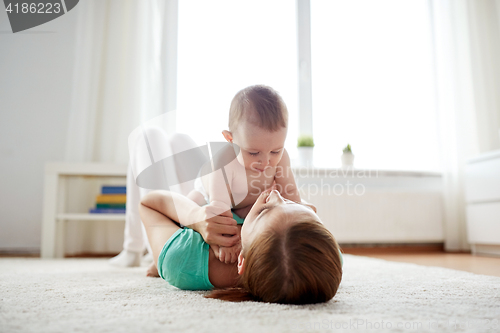 Image of happy mother playing with baby at home
