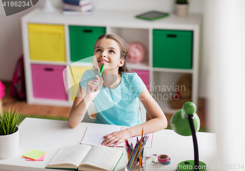 Image of happy girl with book and notebook dreaming at home