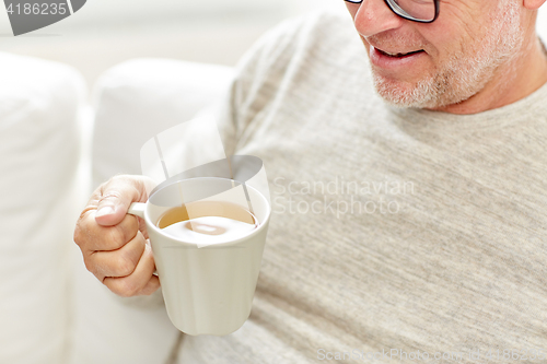 Image of close up of happy senior man drinking tea at home