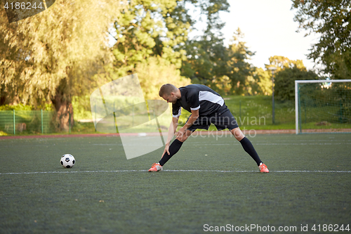 Image of soccer player stretching leg on field football