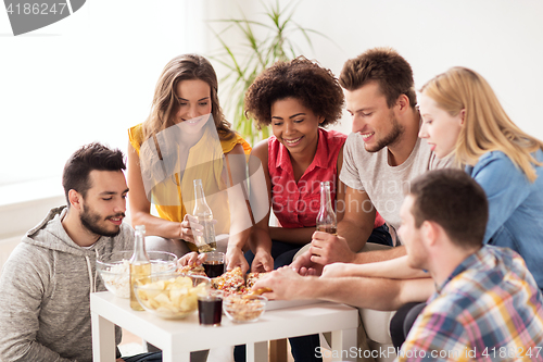 Image of happy friends with drinks eating pizza at home