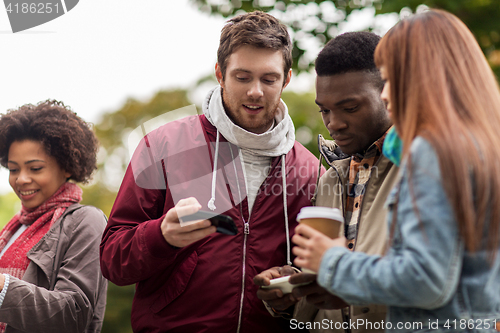 Image of happy friends with smartphone and coffee outdoors