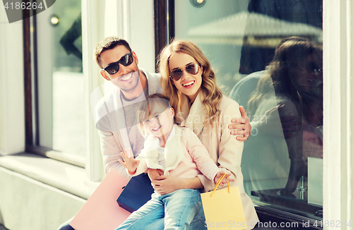 Image of happy family with child and shopping bags in city