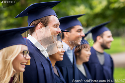 Image of happy students or bachelors in mortar boards