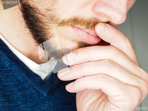 Image of Male person, at closeup with fingers in beard