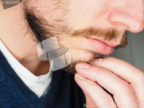 Image of Male person, at closeup with fingers in beard