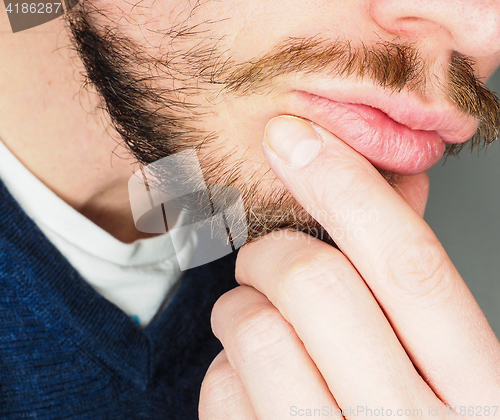 Image of Male person, at closeup with fingers in beard