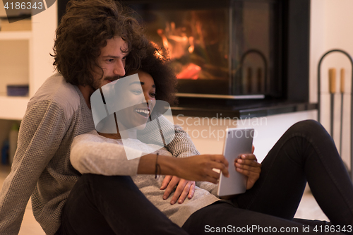 Image of multiethnic couple used tablet computer on the floor