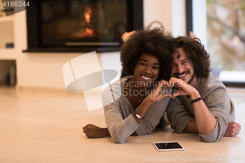 Image of multiethnic couple used tablet computer on the floor