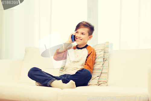 Image of happy boy calling on smartphone at home