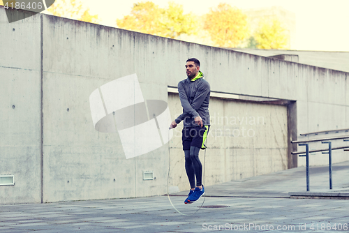 Image of man exercising with jump-rope outdoors