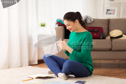 Image of woman with smartphone and travel map at home