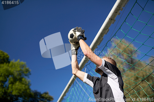 Image of goalkeeper with ball at football goal on field