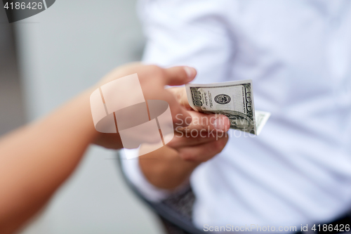 Image of close up of hands giving and receiving dollar money