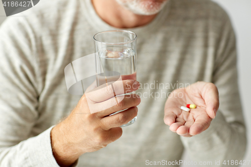 Image of close up of hands with medicine pills and water