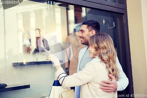 Image of happy couple with shopping bags at shop window