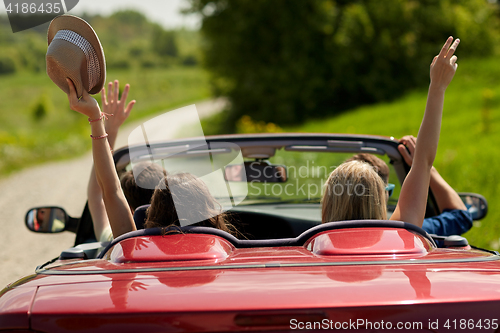 Image of happy friends driving in cabriolet car at country