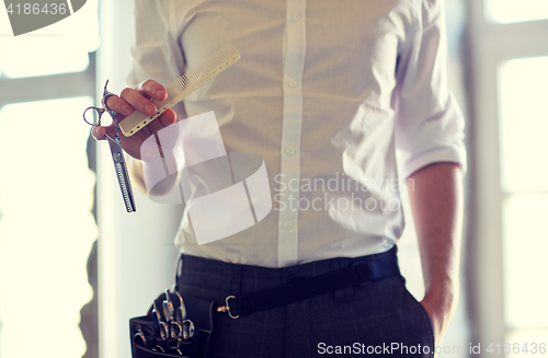 Image of close up of male stylist with scissors at salon