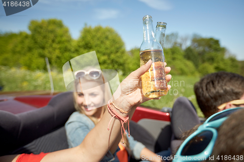 Image of happy young women with drinks in convertible car