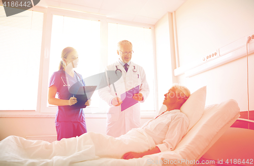 Image of doctor and nurse visiting senior woman at hospital