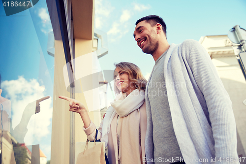 Image of happy couple with shopping bags at shop window