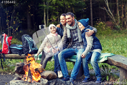 Image of family with smartphone taking selfie near campfire