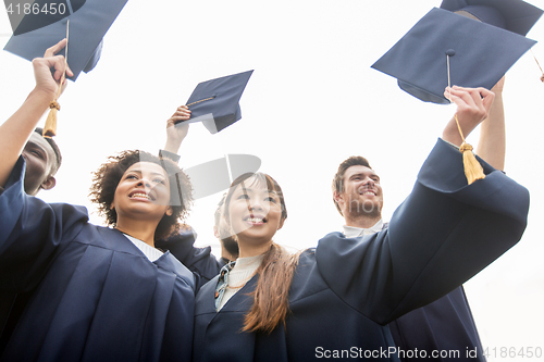 Image of happy students or bachelors waving mortar boards