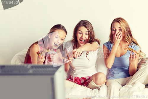 Image of happy friends eating pizza and watching tv at home