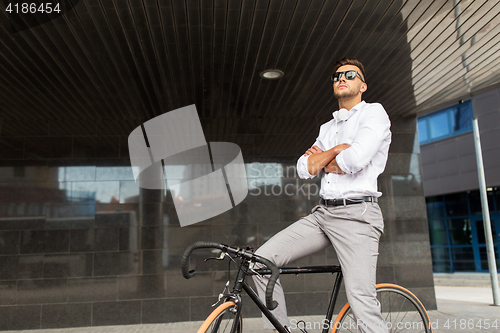 Image of man with bicycle and headphones on city street