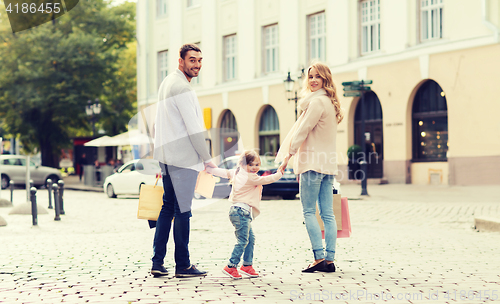 Image of happy family with child and shopping bags in city