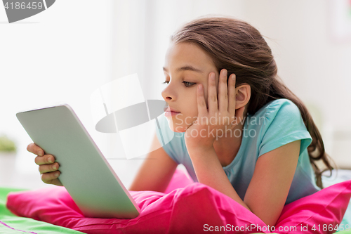 Image of bored girl with tablet pc lying in bed at home