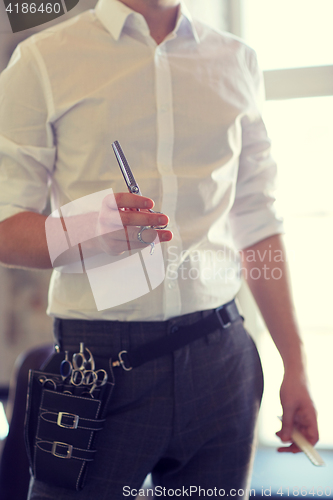 Image of close up of male stylist with scissors at salon