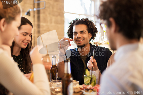 Image of happy friends eating and drinking at bar or cafe