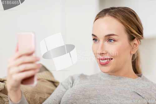 Image of happy woman taking selfie with smartphone at home