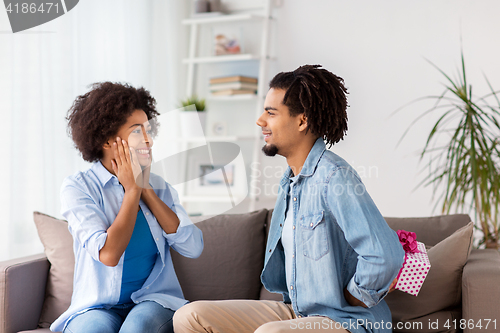 Image of happy couple with gift box at home