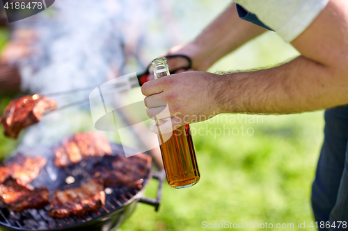 Image of man cooking meat on barbecue grill at summer party