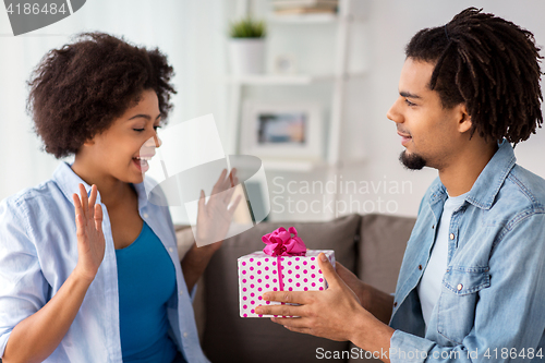 Image of happy couple with gift box at home