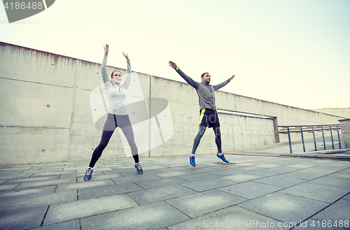 Image of happy man and woman jumping outdoors