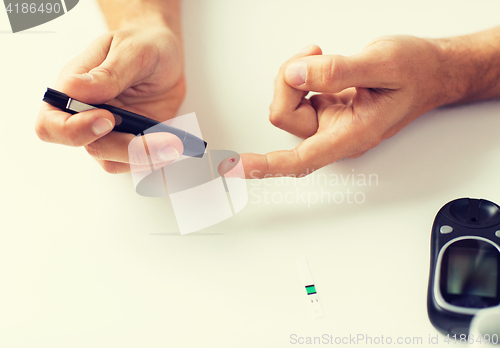 Image of close up of man checking blood sugar by glucometer